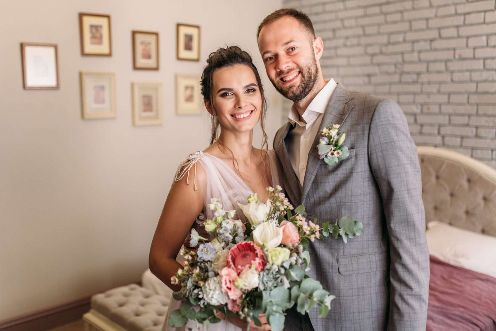 Bride and groom pose in an elegantly decorated room with picture frames and flowers - by wedding photographer Vancouver