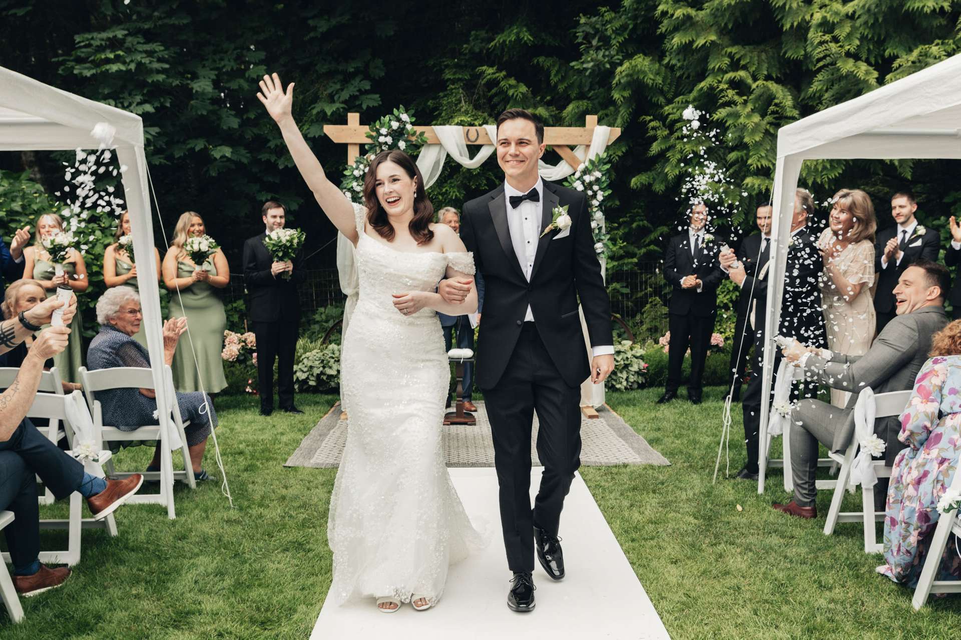 Bride and groom walk down a walkway surrounded by guests holding sparklers. Captured by wedding photographer Vancouver