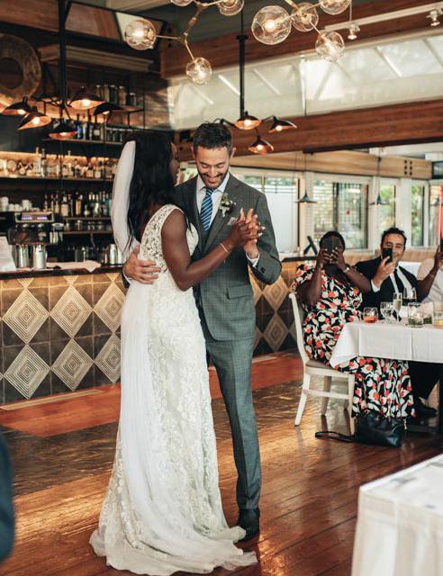 The bride, adorned in an elegant white dress, stands beside her groom, who is dressed sharply in a suit.